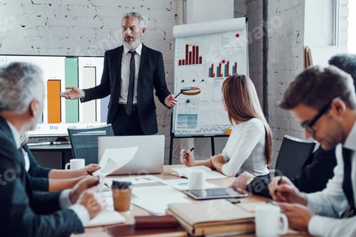 Preview: Modern businessman conducting a presentation while having staff meeting in the board room