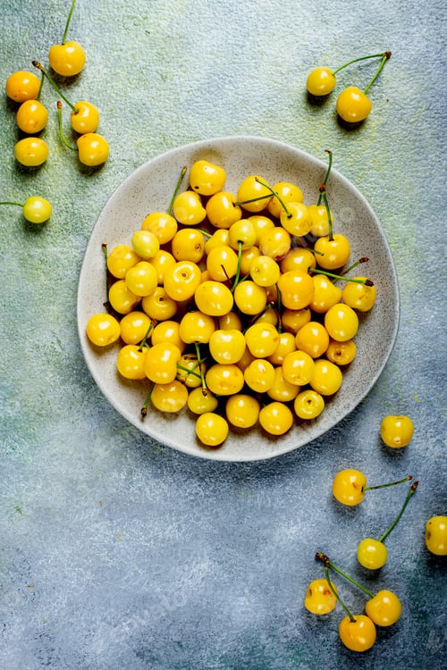 Preview: yellow cherry, cherry berry, scattered on a plate, top view, no people,