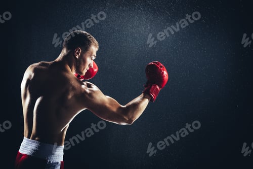 Preview: Man boxing with red gloves on his hands in the rain.