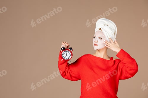 Preview: front view young female with face mask holding clocks on pink background woman moisturizing color