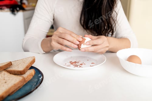 Preview: Woman peeling boiled egg on white table.