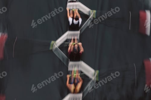 Preview: Blurred motion overhead view of a rowing crew in a sculling boat on the water, mid stroke