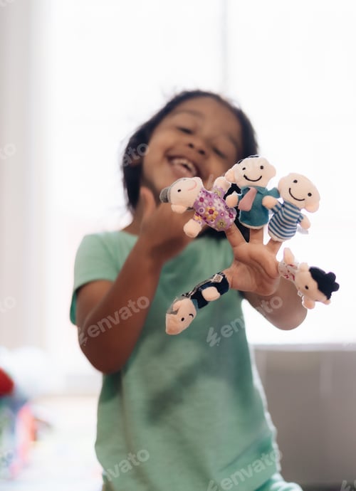 Preview: Diverse Toddler girl playing with finger puppets having fun at home