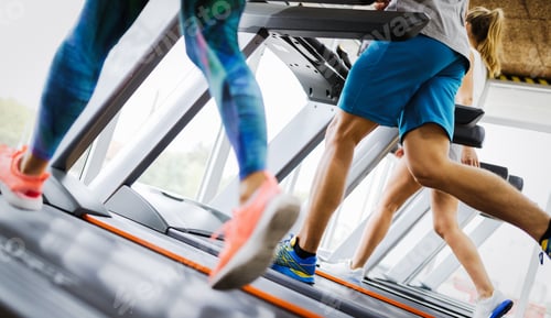 Preview: Healthy man and woman running on a treadmill in a gym
