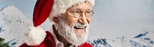 Preview: joyful white bearded man in red hat and glasses smiling happily looking away, winter concept, banner