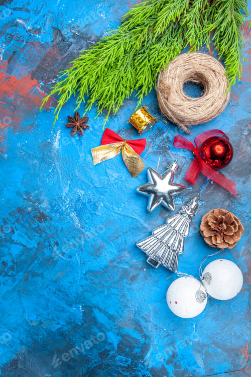 Preview: top view pine tree branches straw thread xmas tree toys anise seed on blue-red background with copy