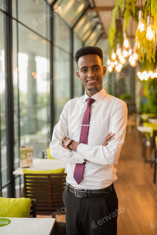 Preview: Handsome young African businessman in coffee shop restaurant