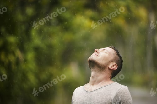 Preview: Man in wet clothing with eyes closed enjoying heavy rain