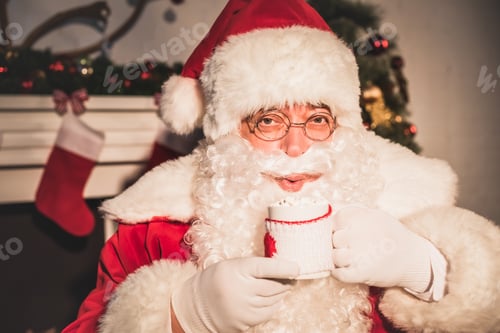 Preview: santa drinking hot beverage with marshmallows and looking at camera