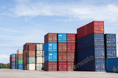 Preview: Colorful stacked shipping containers are neatly arranged under a clear blue sky at a freight yard.