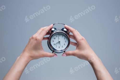Preview: The female hands and old style alarm clock