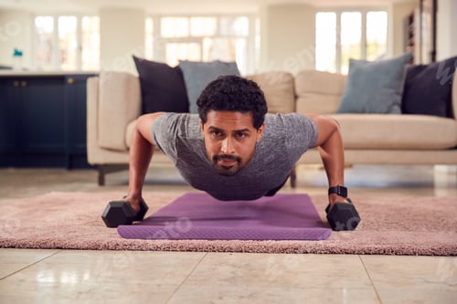 Preview: Man In Fitness Clothing At Home In Lounge Exercising With Hand Weights