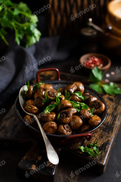 Preview: Mushrooms champignon fried in soy sauce, with pepper and steamed onions in an old metal bowl on an o
