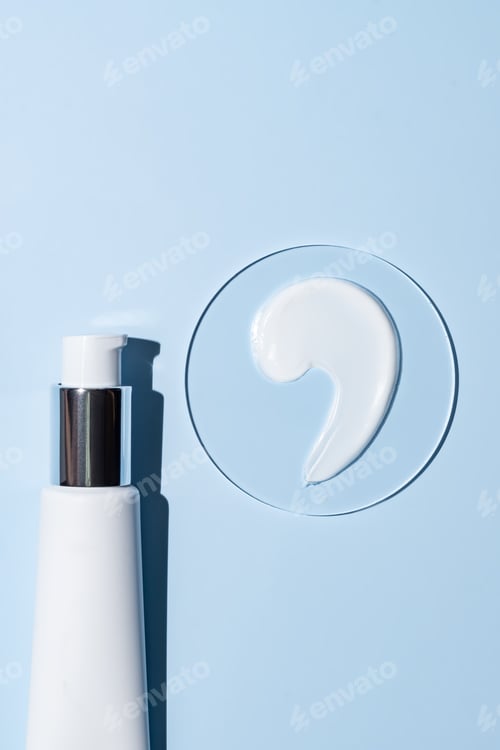 Visualização: Tubo de pompa branco de creme facial ou para mãos e amostra de textura em placa de Petri sobre fundo azul. Cosmético