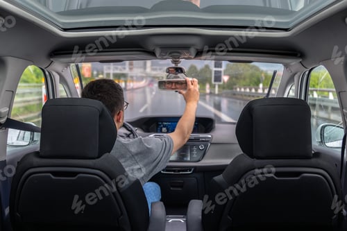Preview: Driver adjusts mirror on rainy ride. Mirror adjustment.