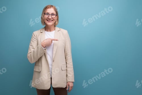 Preview: kind mature woman in stylish shows her hand to the side on a bright studio background with copy