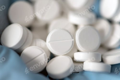 Preview: Closeup doctor or nurse hands in blue rubber gloves with handful pills