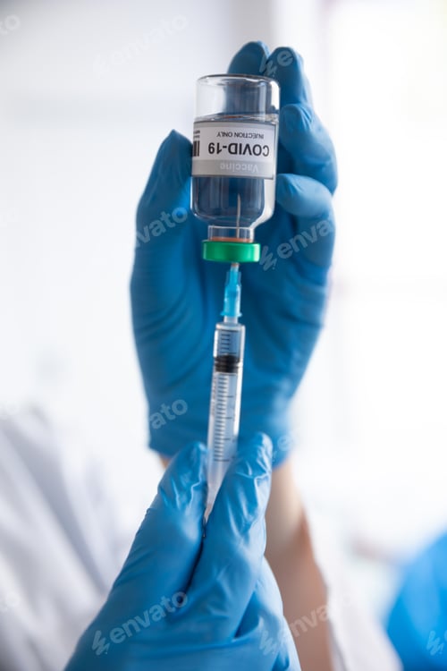 Preview: Close up of doctor injecting syringe into a vial bottle with text Covid-19