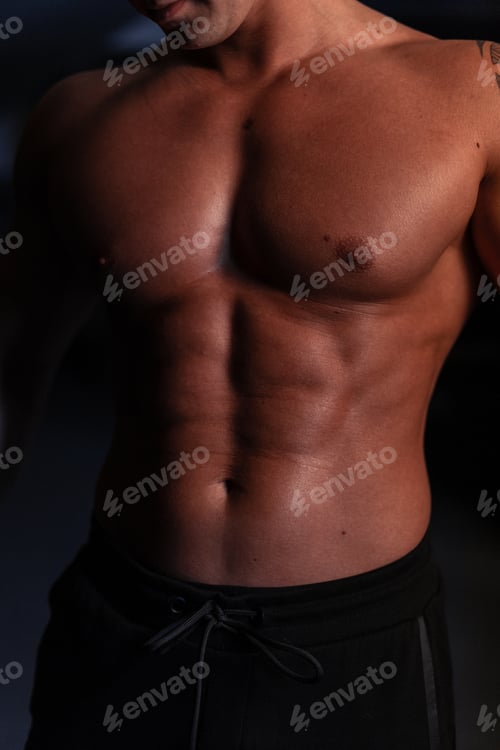 Preview: Athletic sexy healthy body of young strong man athlete trainer with naked torso in the dark