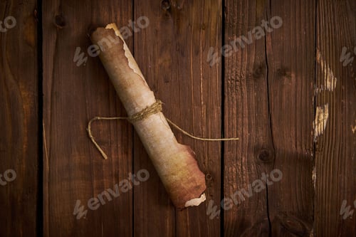 Preview: Brown roll of aged paper wrapped in thick twine sits atop a rustic wooden tabletop.