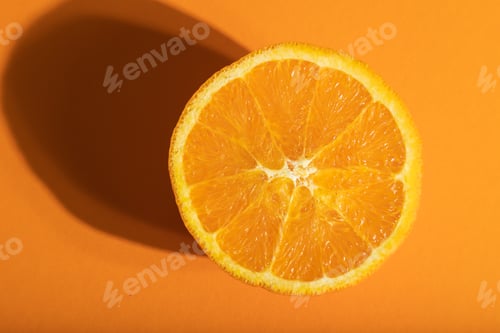 Preview: Ripe cut orange on orange pastel background. Top view, close up, hard light.