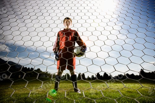 Preview: A boy in a soccer shirt holding a soccer ball, standing in goal.