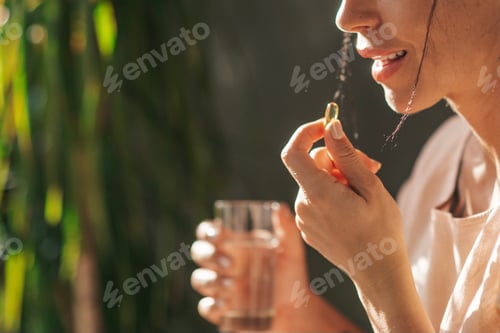 Preview: close-up girl taking a jelly capsule vitamin