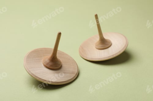 Preview: Two wooden spinning tops on green background, closeup