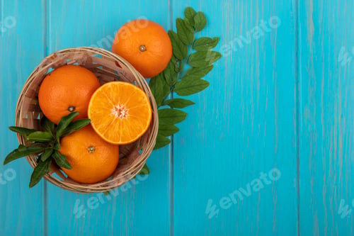Preview: top view copy space oranges in a basket with a sprig of leaves on a turquoise background