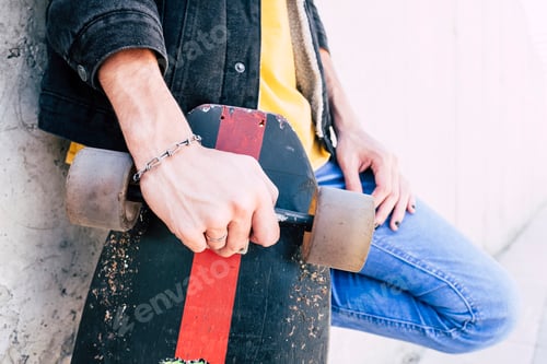 Preview: Close up of young man hands holding used trendy skateboard