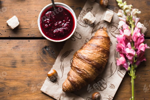 Preview: Croissant, Jam, and Flowers on a Rustic Table