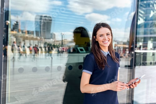 Preview: UK, London, portrait of smiling woman with smartphone in the city