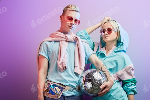Preview: Young fashionable couple of dancers posing with disco ball on violet background