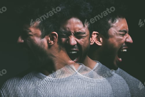 Preview: Studio shot of a young man experiencing mental anguish and screaming against a black background