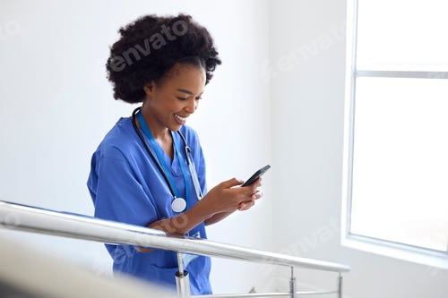 Preview: Female Doctor Or Nurse Browsing On Mobile Phone On Stairs In Hospital