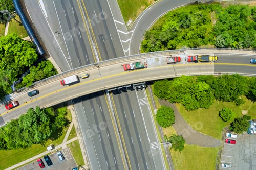 Preview: Traffic flows smoothly over an elevated roadway surrounded by greenery in urban area