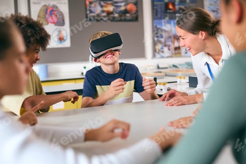 Preview: Amazed Male Secondary Or High School Pupil Wearing VR Headset In Science Class With Female Teacher