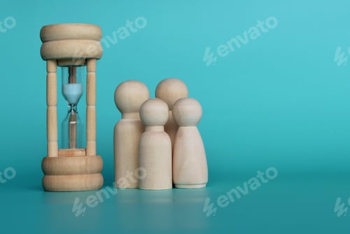Preview: Wooden dolls and hourglass on green background with copy space