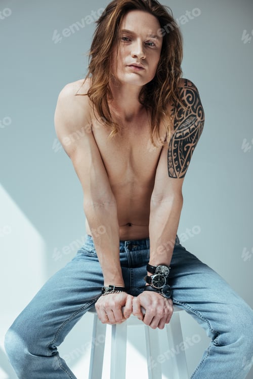 Preview: sexy shirtless man with long hair and tattoo on hand, on grey
