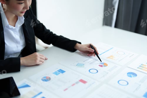 Preview: Portrait of a thoughtful Asian businesswoman looking at financial statements and making marketing