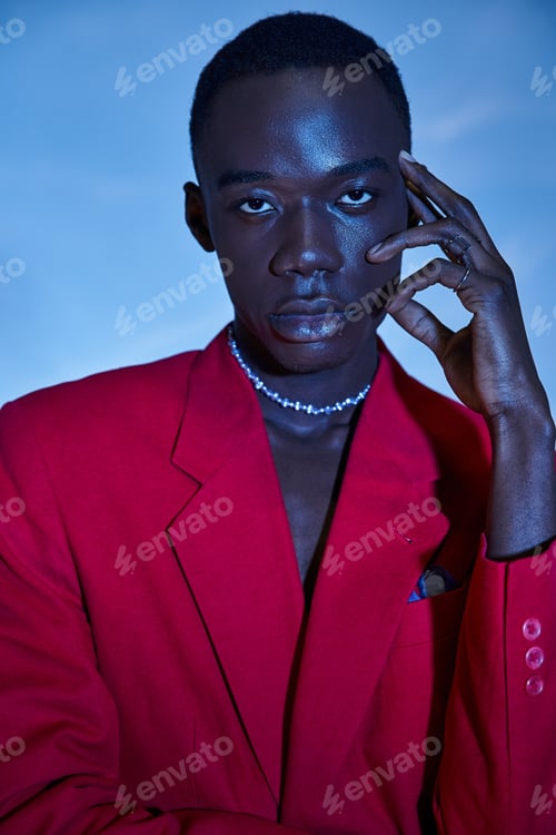 Preview: attractive young african american man in red vibrant blazer posing on blue watery background