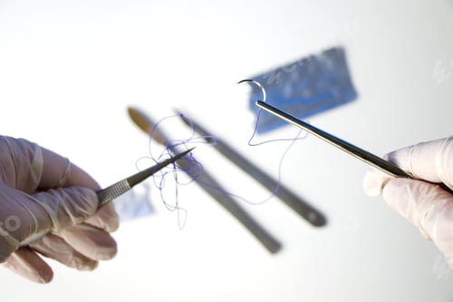 Preview: Closeup shot of a doctor holding a surgical needle and thread on a white background