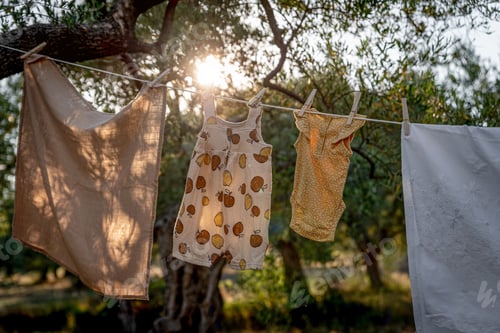 Preview: Baby clothes on clothesline drying in garden. Newborn childhood concept