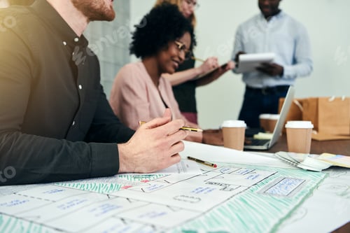 Preview: Diverse group of designers working with blueprints in an office