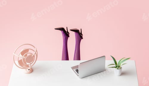 Preview: laptop and a fan on the table next to female legs sticking out from under the table