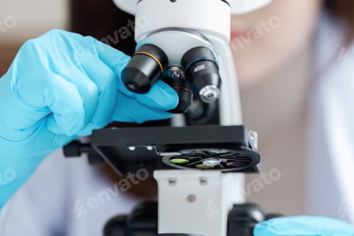Preview: Scientist Adjusting Microscope in Laboratory with Blue Gloves for Scientific Research and Analysis