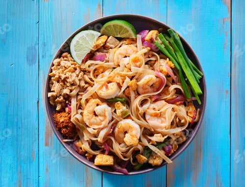 Preview: shrimp pad thai on plate in flat lay composition with copy space atop of colorful wooden table