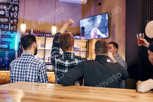 Preview: Football fans watching TV. Group of people together indoors in the pub have fun at weekend time