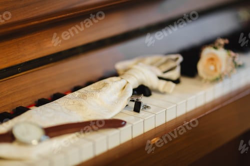 Preview: Groom's accessories. Stylish watch, tie, boutonniere and cufflinks on the keys for piano. Groom's