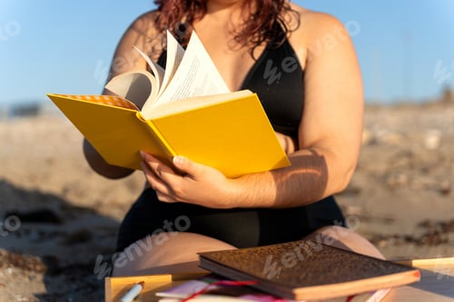 Preview: Curvy woman reading a book at the beach: body positive concept